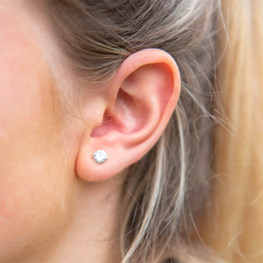 Oreille avec piercing au lobe portant une boucle d'oreille avec brillant